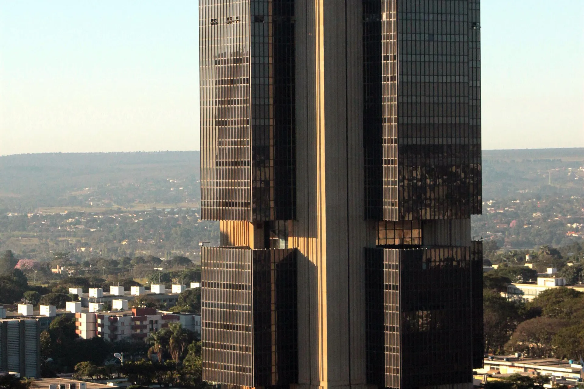 Torre de vidro e concreto da sede do Banco Central do Brasil, em Brasília, com a cidade ao fundo.