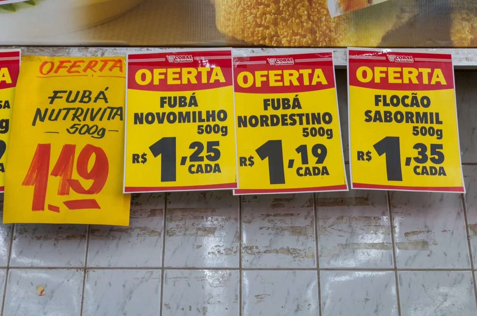 Cartazes de oferta com preços de fubá e flocão em supermercado do Recife
