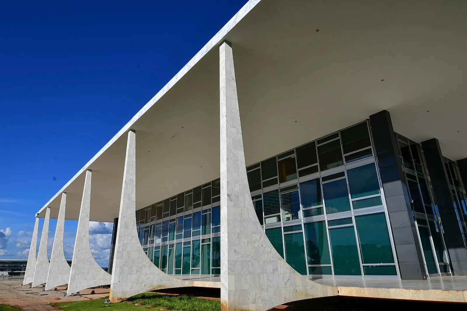 Fachada do Supremo Tribunal Federal em Brasília, com grandes colunas de mármore branco sob céu azul.